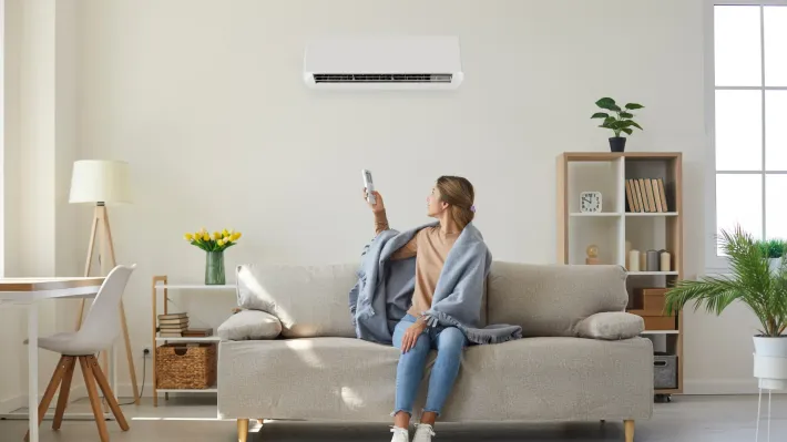 A woman is sitting on a couch holding a remote control.