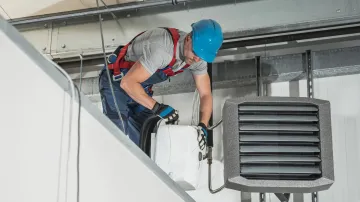 A man is working on a heater in a building.