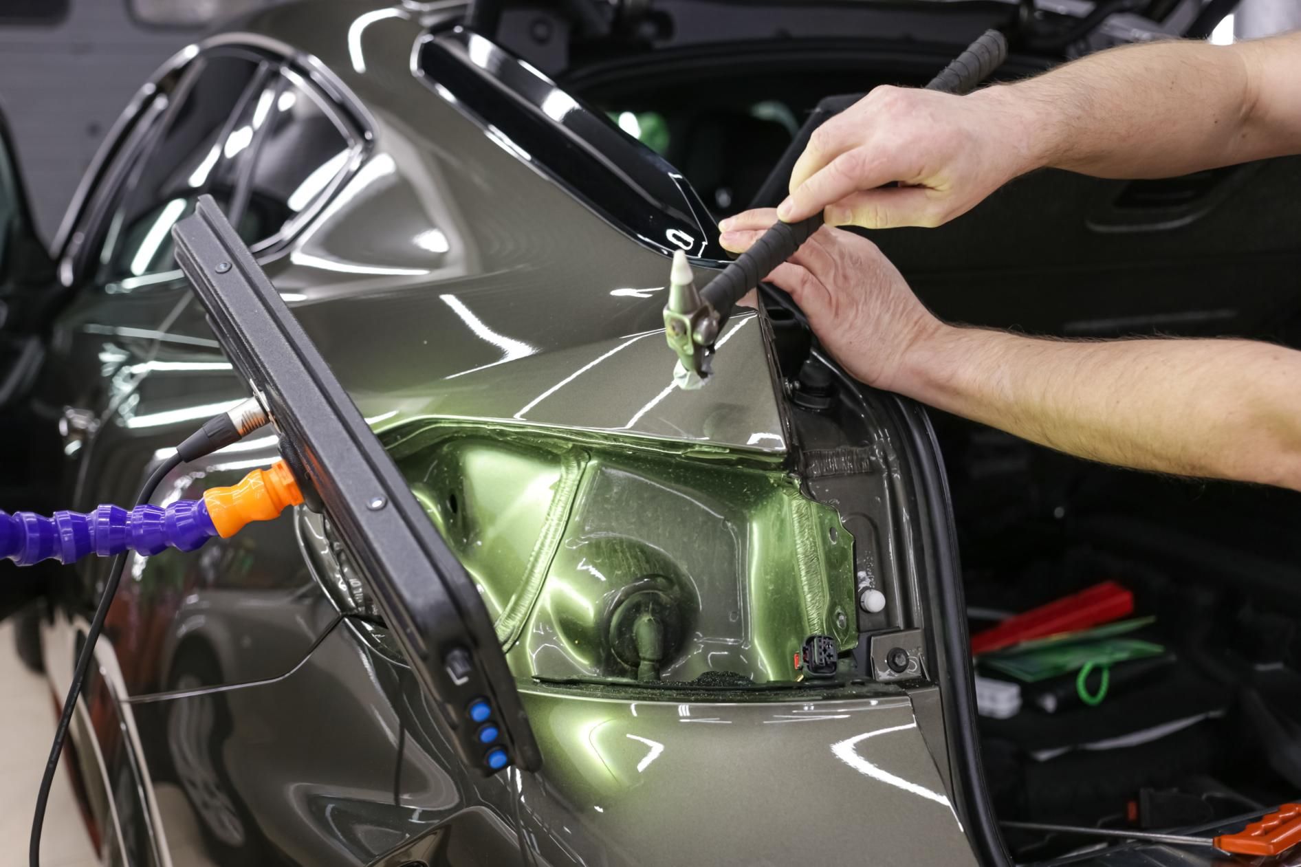 A man is working on the hood of a car.