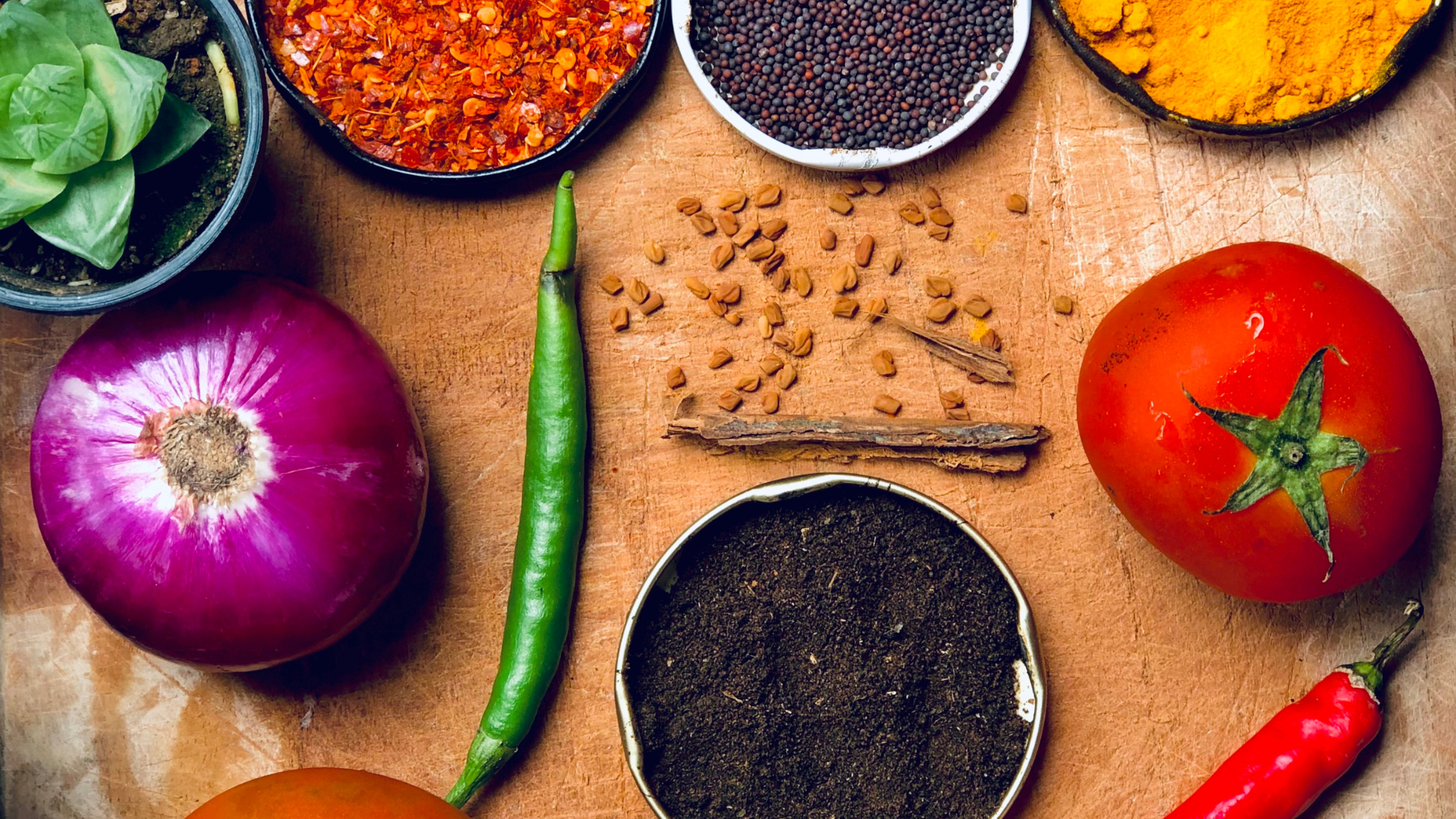 Assortment of spices in bowls and peppercorn grinder on a white surface.