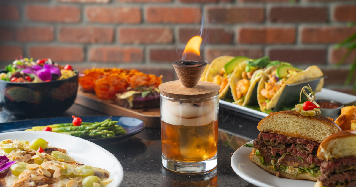 A table topped with plates of food and a glass of beer.