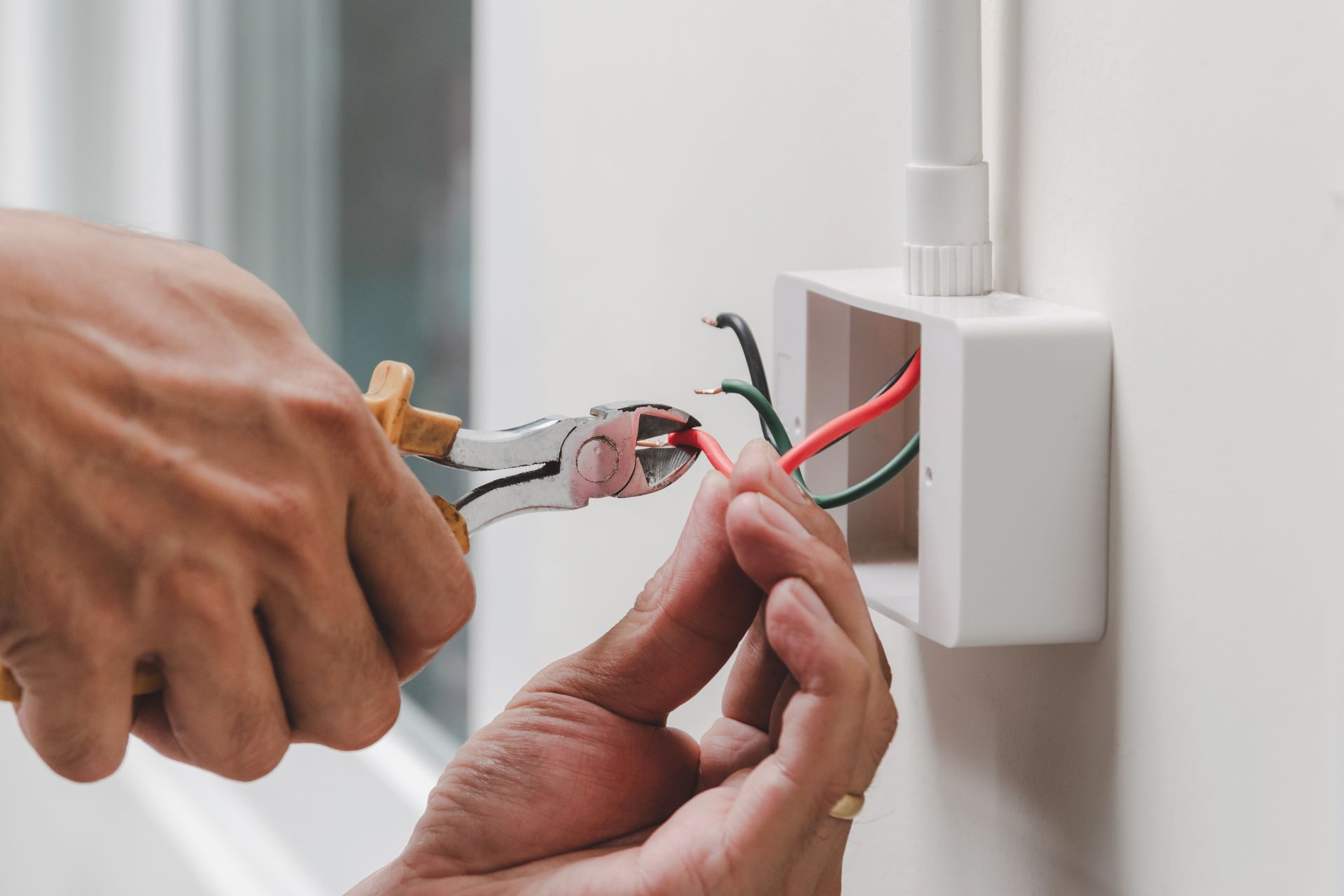 A person is working on an electrical box on a wall.