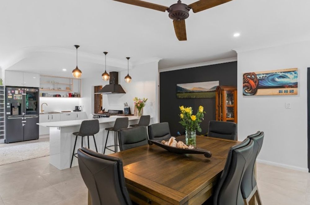 A Dining Room with A Wooden Table and Chairs and A Ceiling Fan — Cairns Vacate Clean in Manunda, QLD