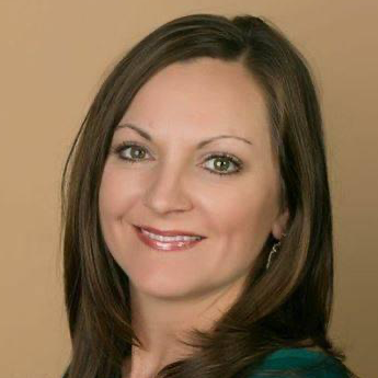 A woman wearing hoop earrings and a white shirt is smiling for the camera.