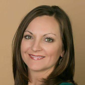 A woman wearing hoop earrings and a white shirt is smiling for the camera.