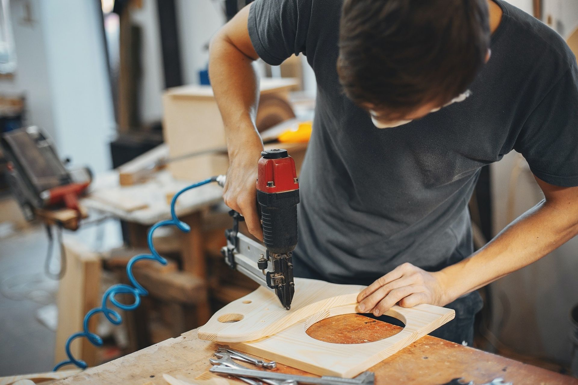 Person using a power tool to cut a wooden board in a workshop