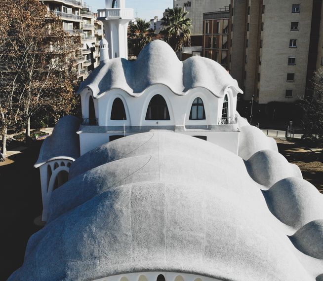 Unique white building with rounded, undulating roof, in an urban setting.