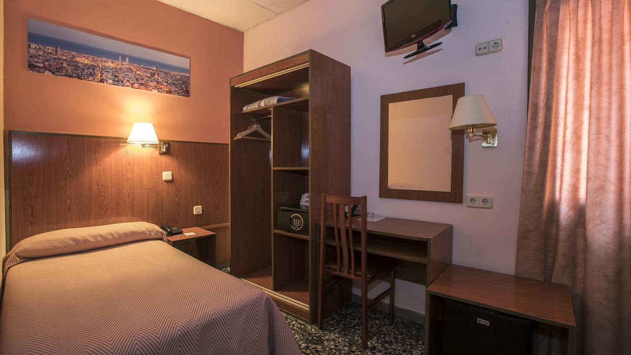 Hotel room with a single bed, closet, desk, and TV; brown and pink tones.