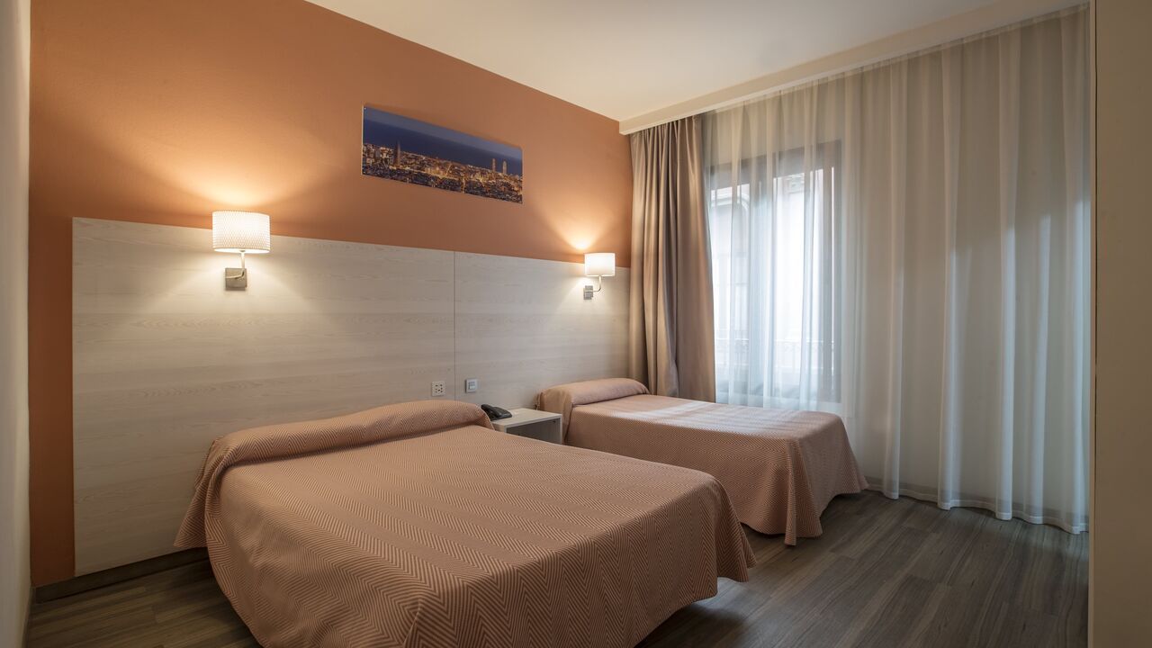 A hotel room with two beds, a window, and peach-colored walls.