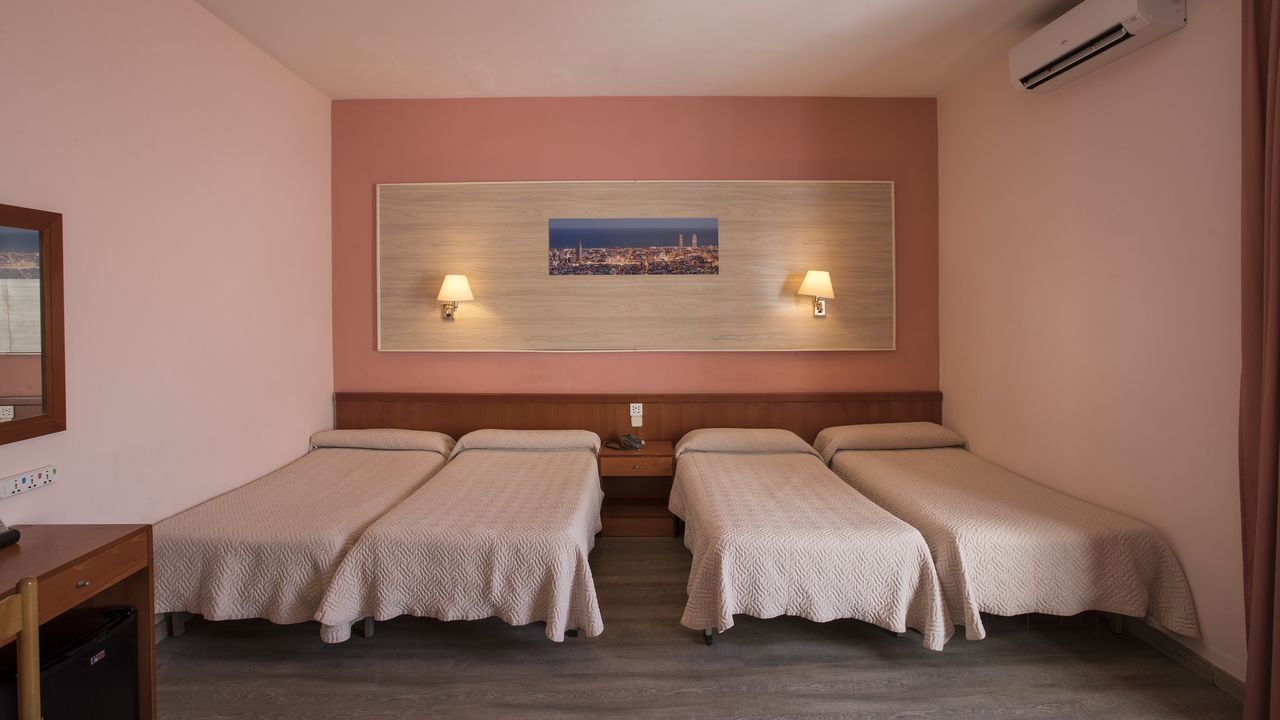 A hotel room with three beds, pale pink walls, and a cityscape photo above the beds.