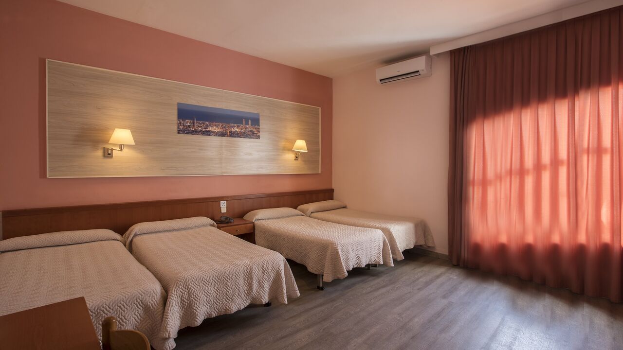 A hotel room with three beds, pink walls, and a window with red curtains.