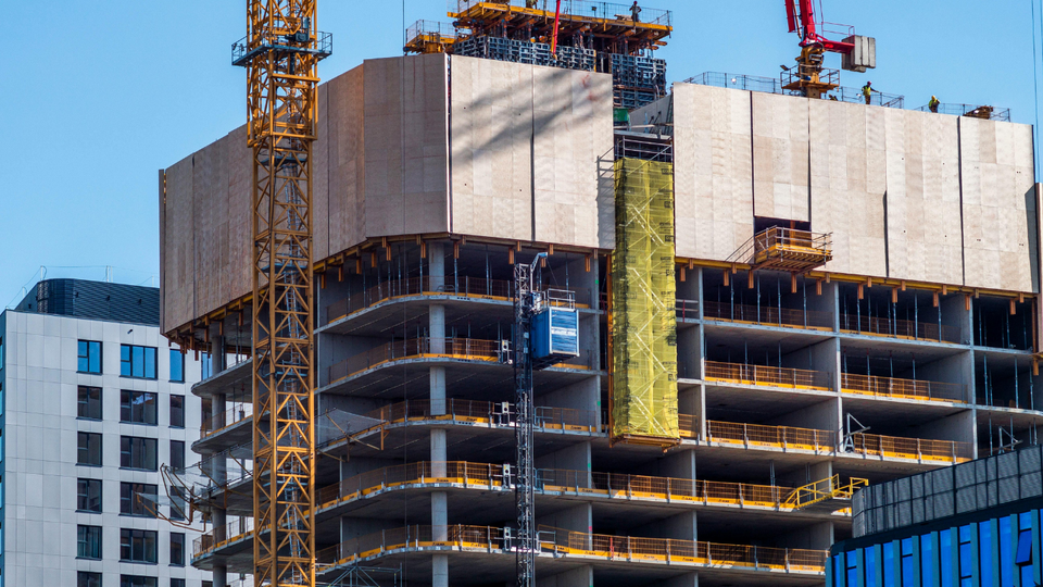 Construction site: multi-story building under construction with a crane and elevator.