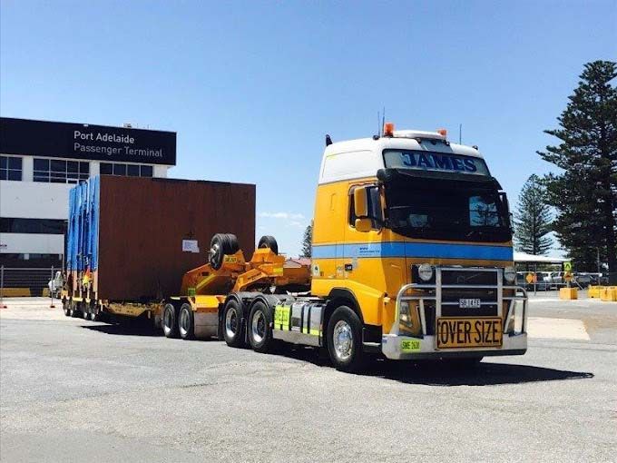 A yellow james truck is driving down a road