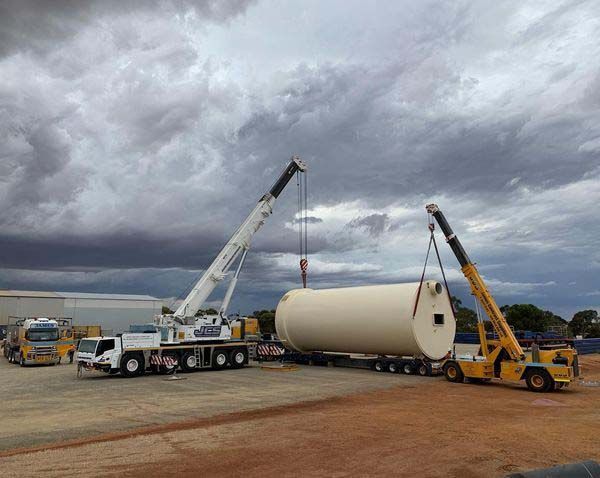 A large white tank is being lifted by a crane.