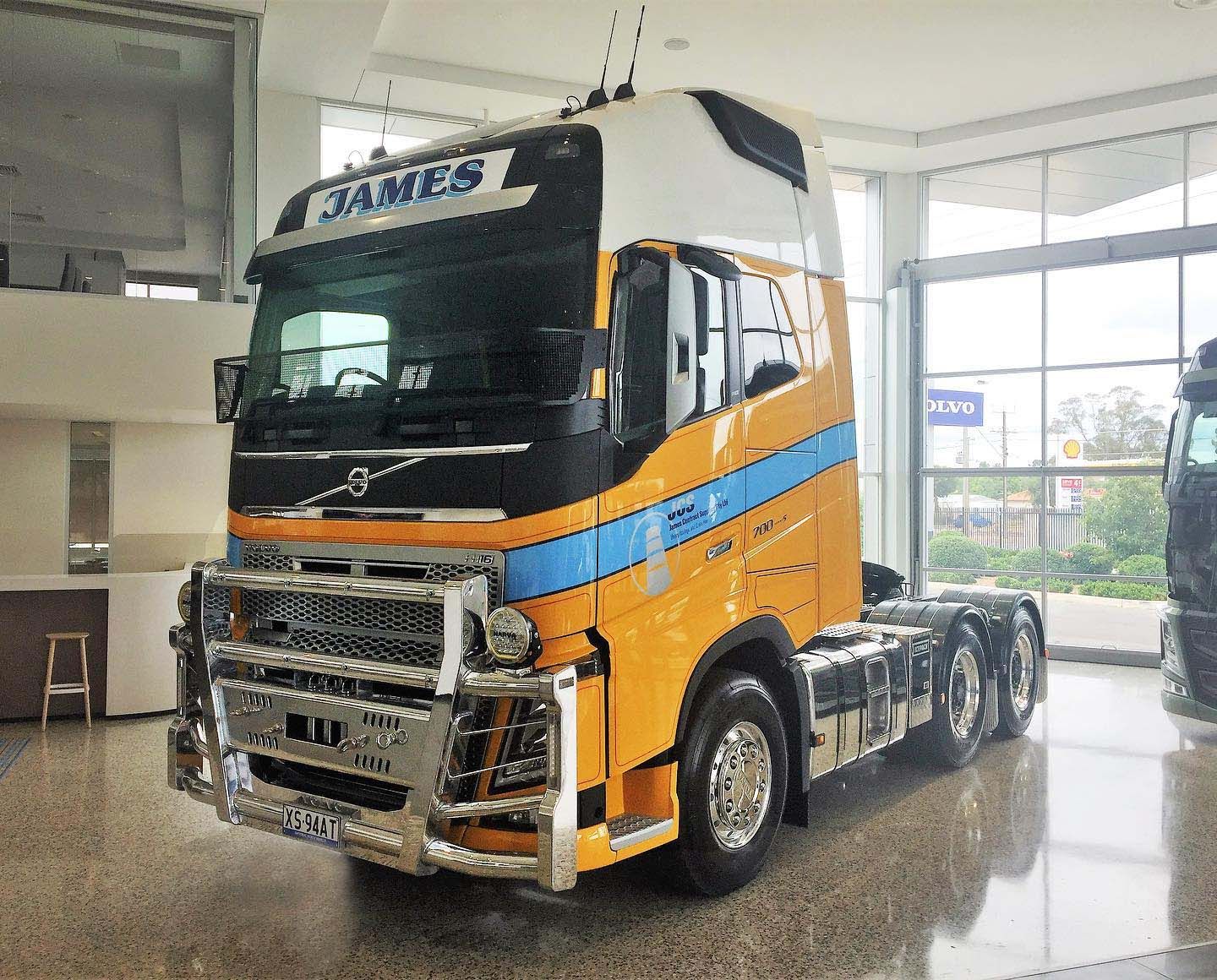 A yellow and blue semi truck is parked in a showroom.