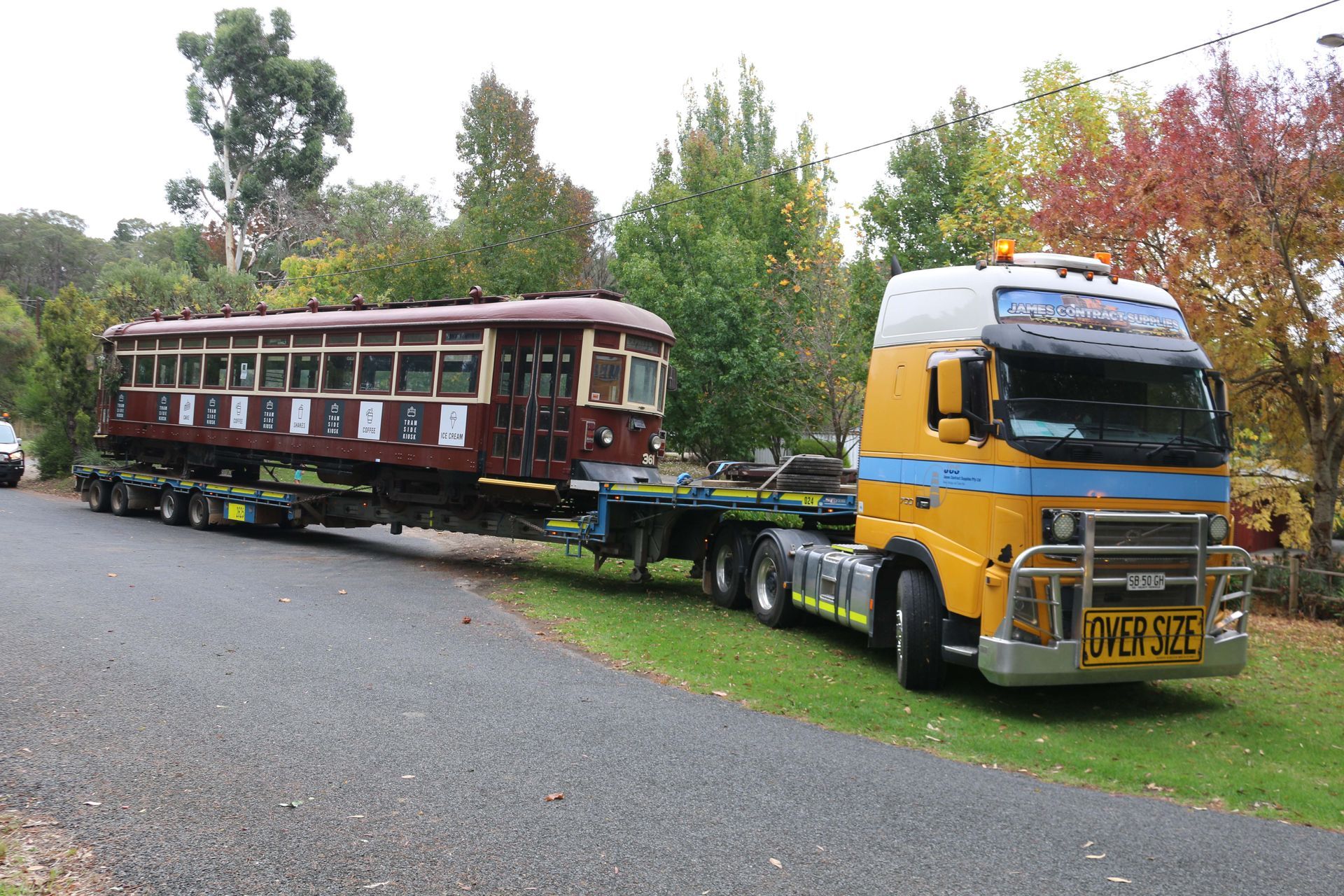 A yellow truck is carrying a train on a trailer