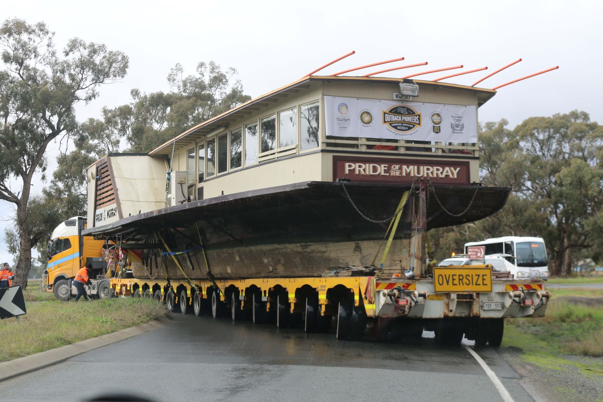 A truck is carrying a building that says pride & murray