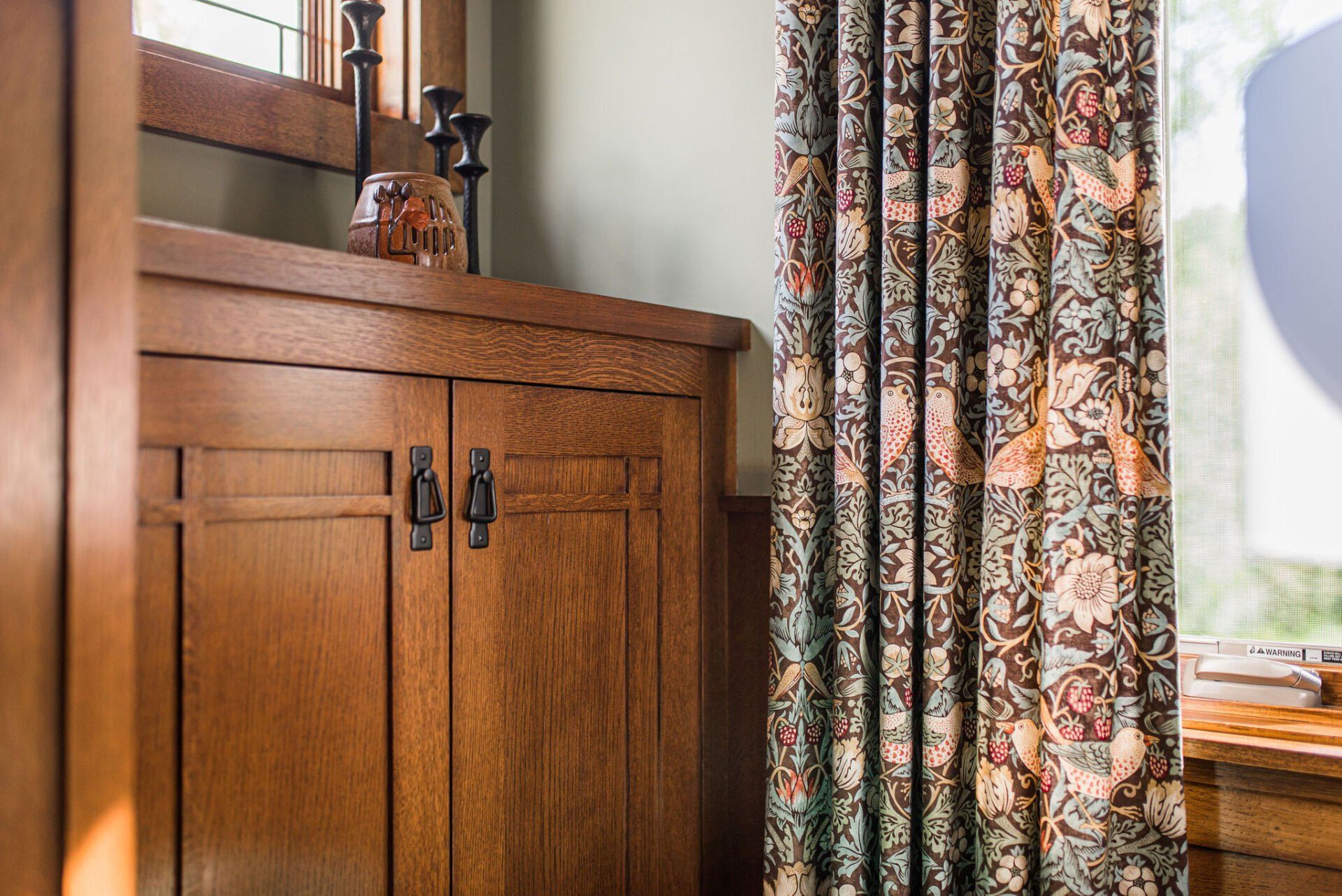 A room with a wooden cabinet and a window with curtains.