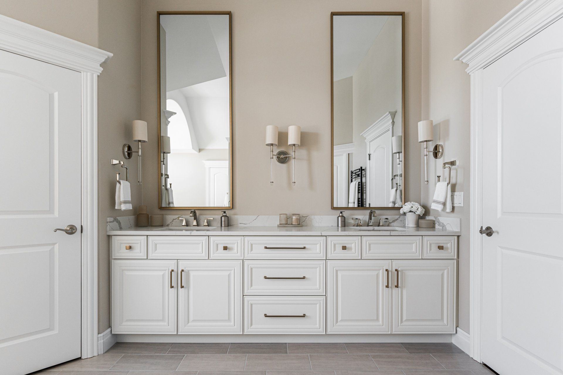A bathroom with two sinks , two mirrors , and white cabinets.