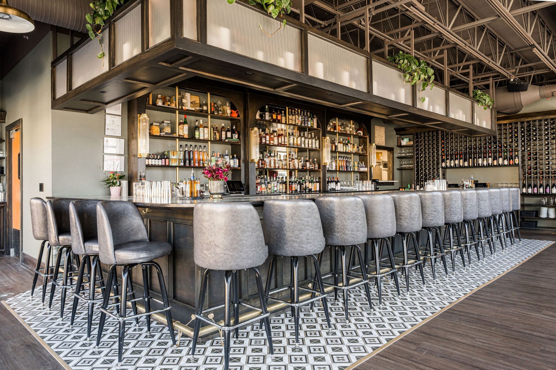 A long bar with a lot of chairs and bottles on the shelves.