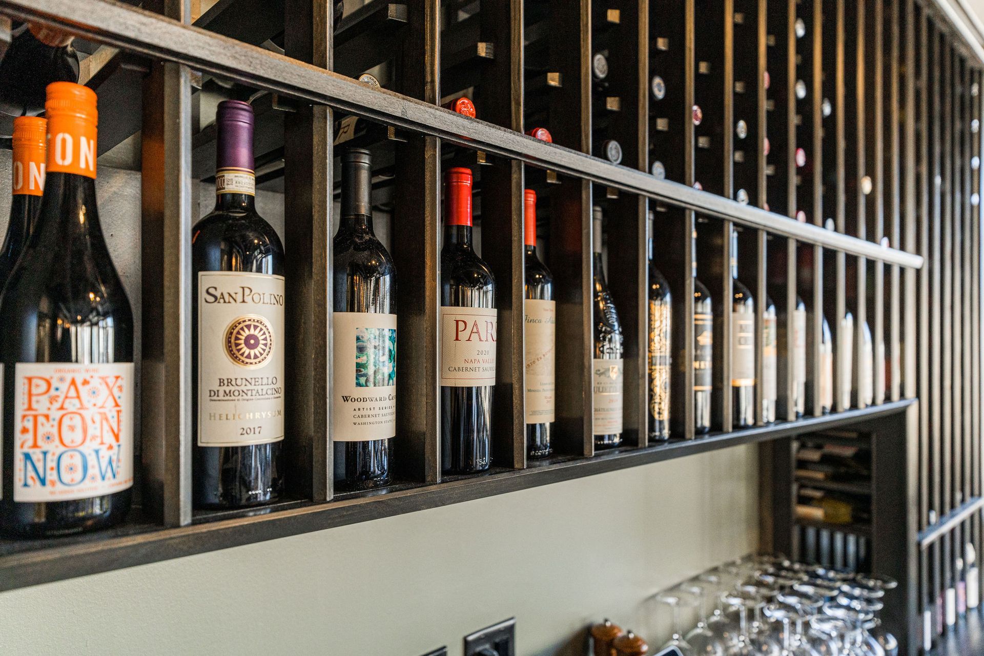 A row of wine bottles are lined up on a shelf.