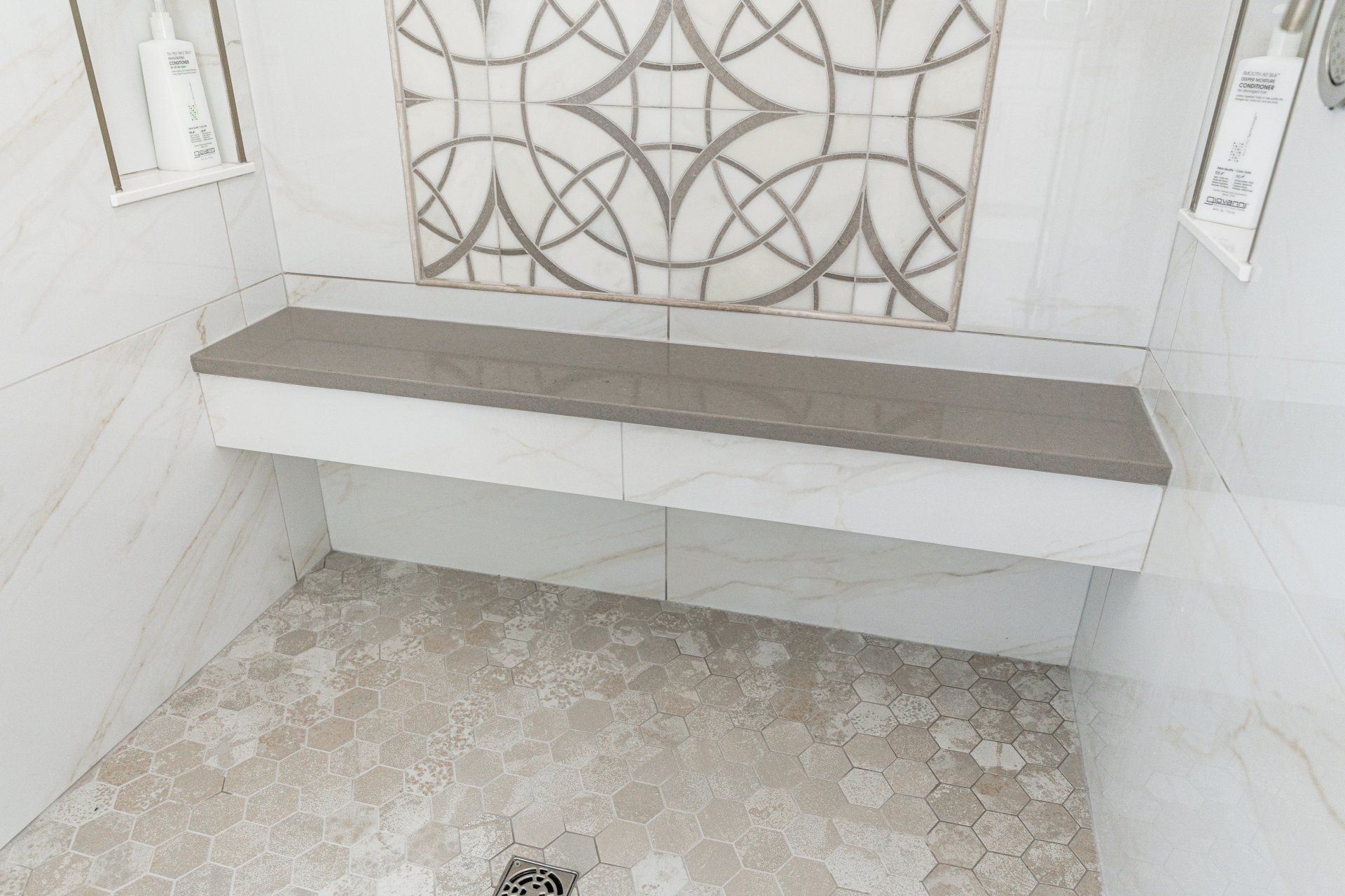 A shower with a bench and a drain in it.