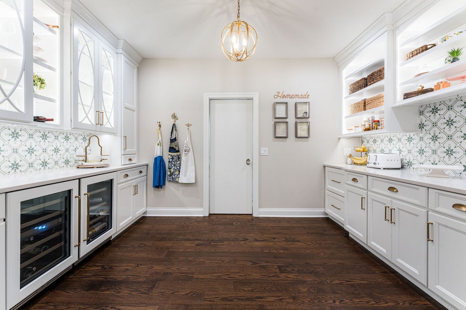 A kitchen with white cabinets , hardwood floors , a refrigerator and a sink.