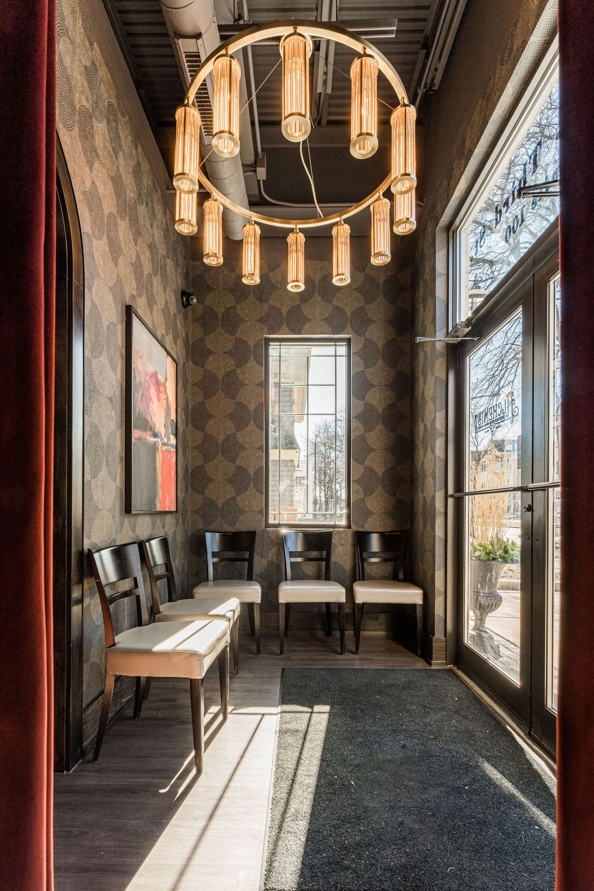 A long hallway with chairs and a chandelier hanging from the ceiling.