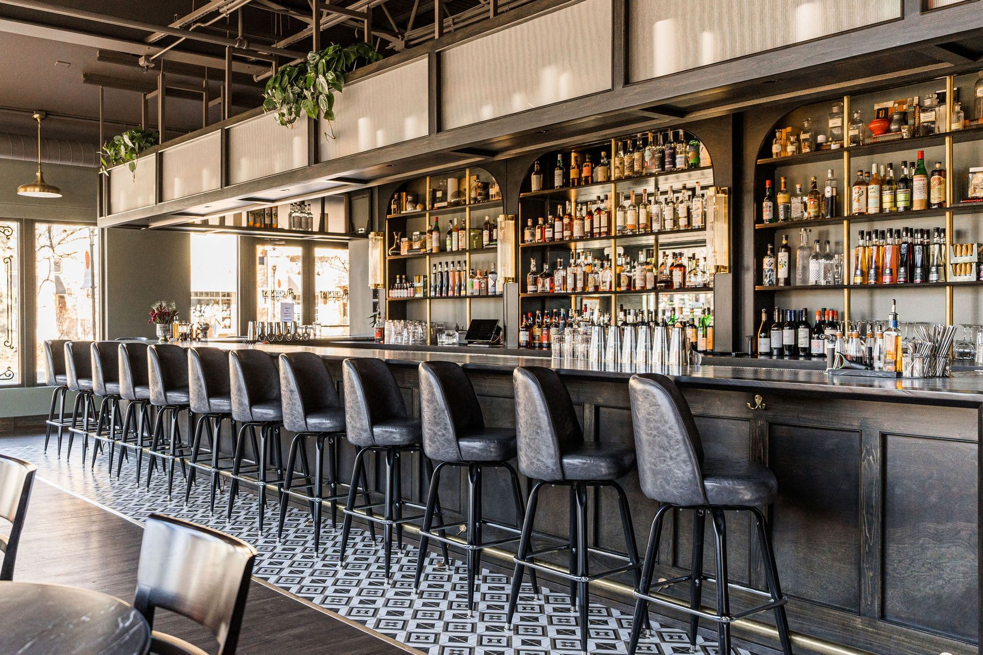 A long bar in a restaurant with a lot of bottles on the shelves.