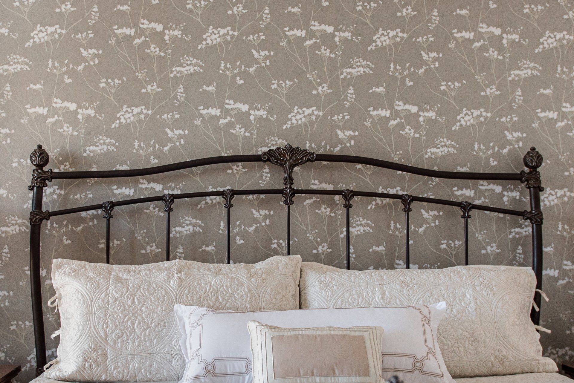 A bed with a metal headboard and white pillows in a bedroom.