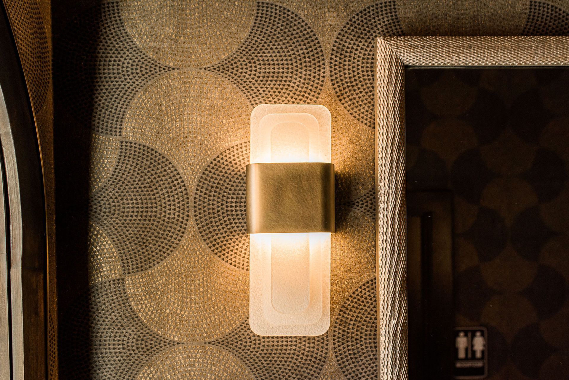 A wall light is hanging on a wall next to a mirror.