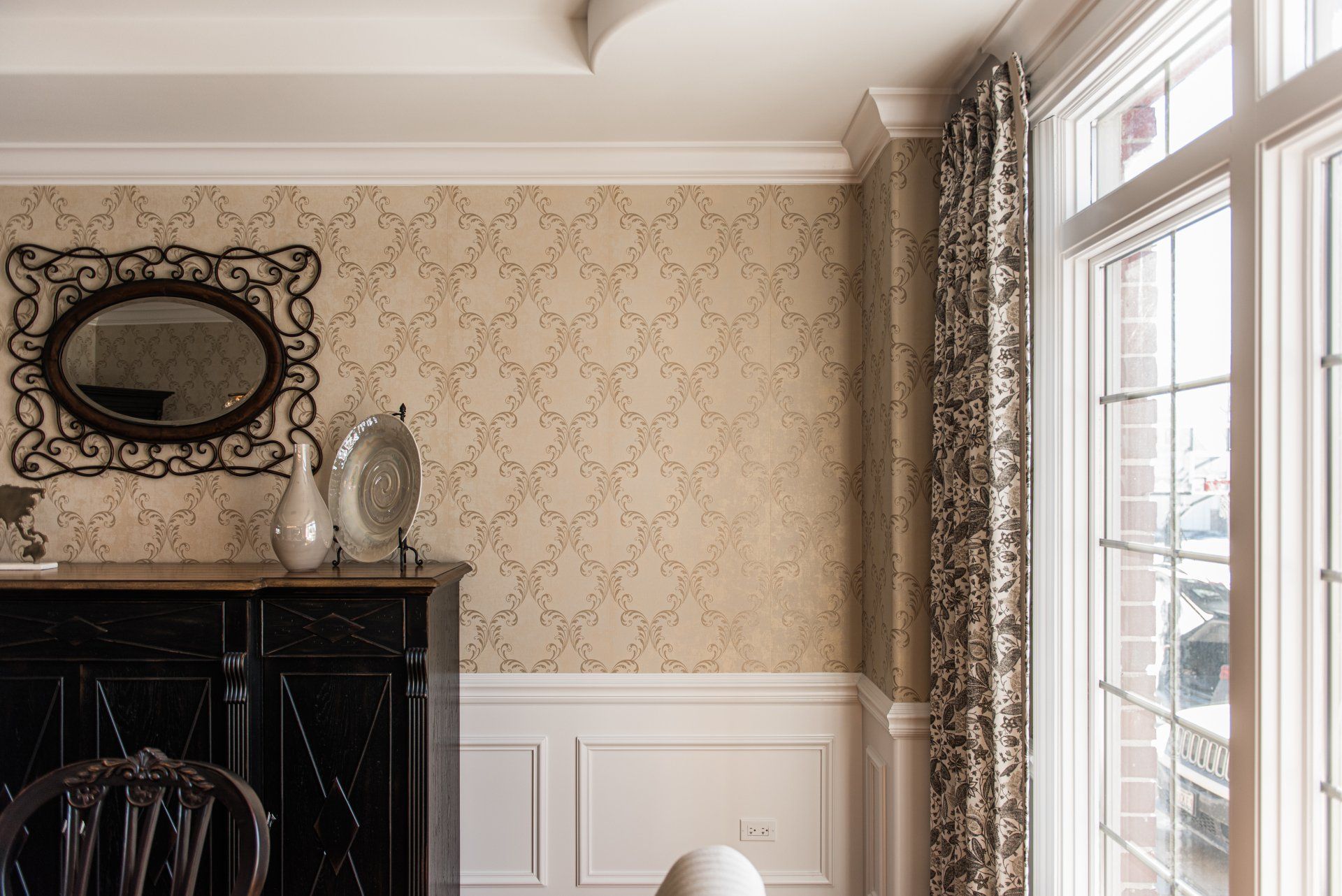 A dining room with a large window and a mirror on the wall