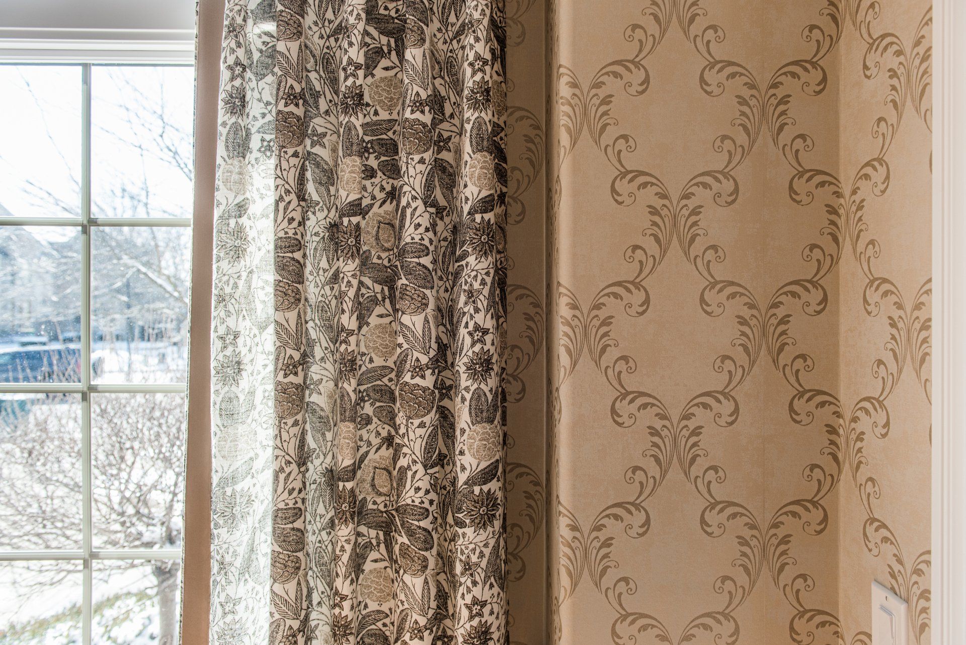 A pair of curtains are hanging on a wall next to a window.