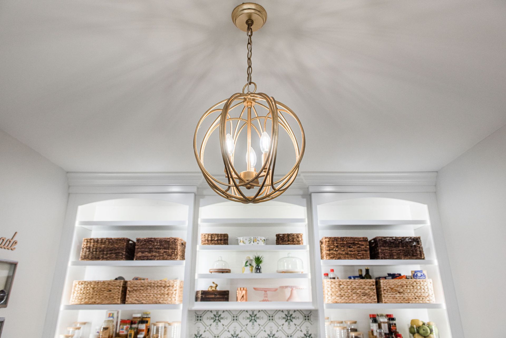 A chandelier is hanging from the ceiling in a room with shelves.