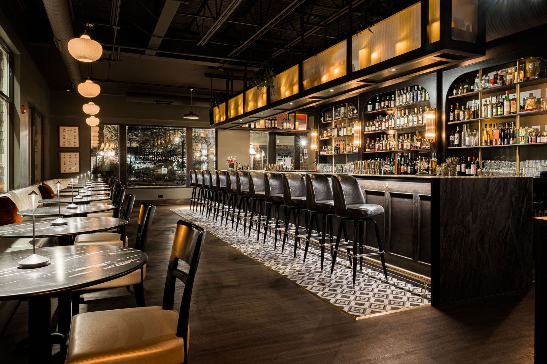 A restaurant with a long bar and tables and chairs