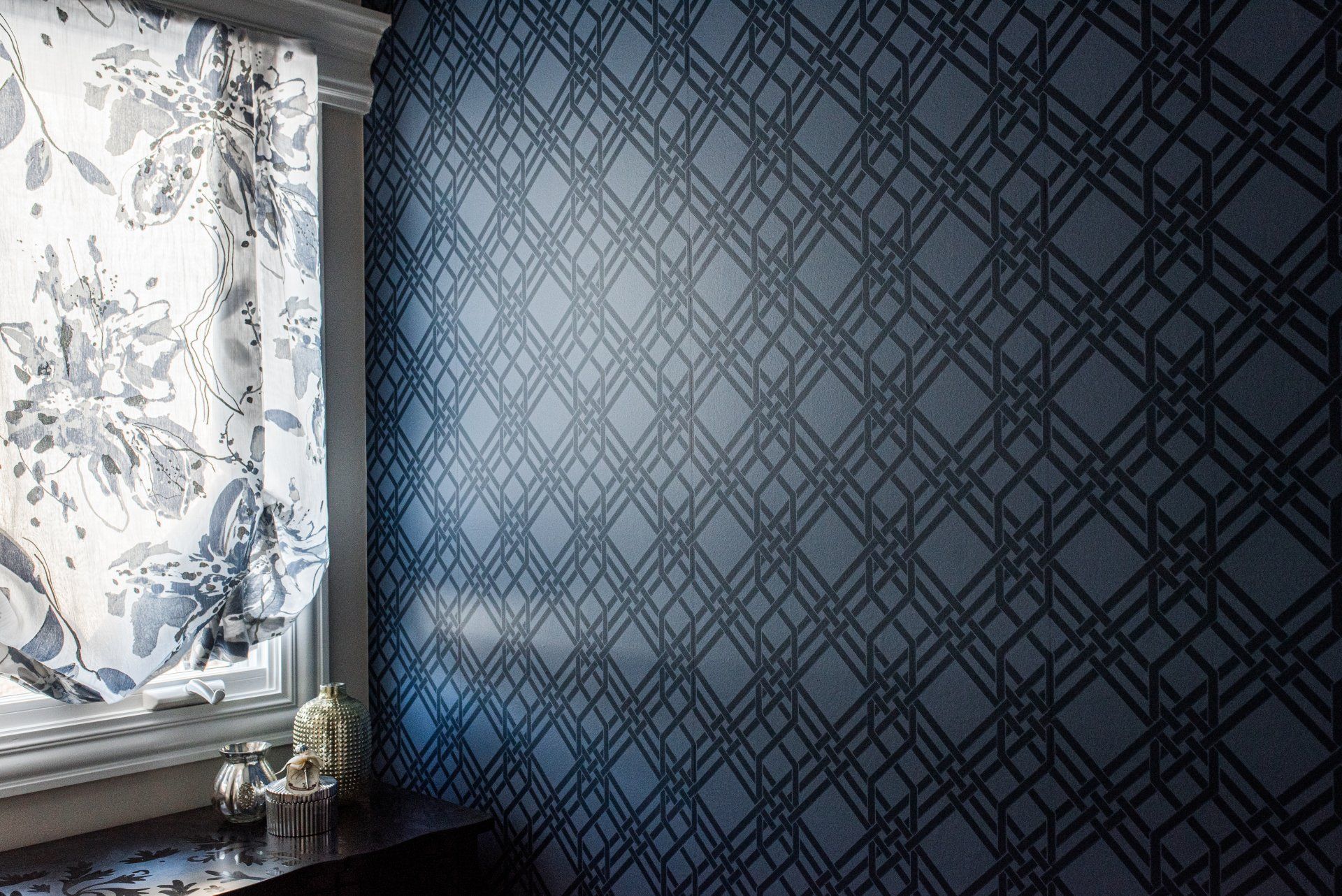 A room with a window and a blue wall with a pattern on it.