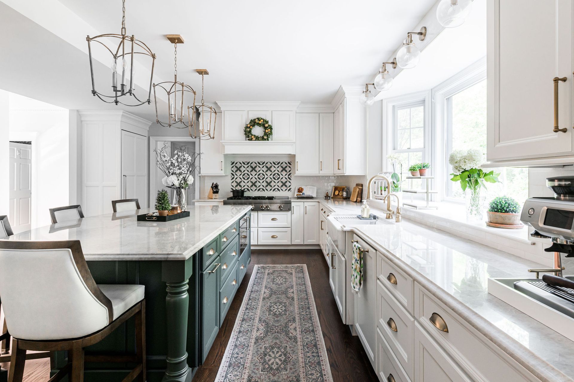 A kitchen with white cabinets and a green island.
