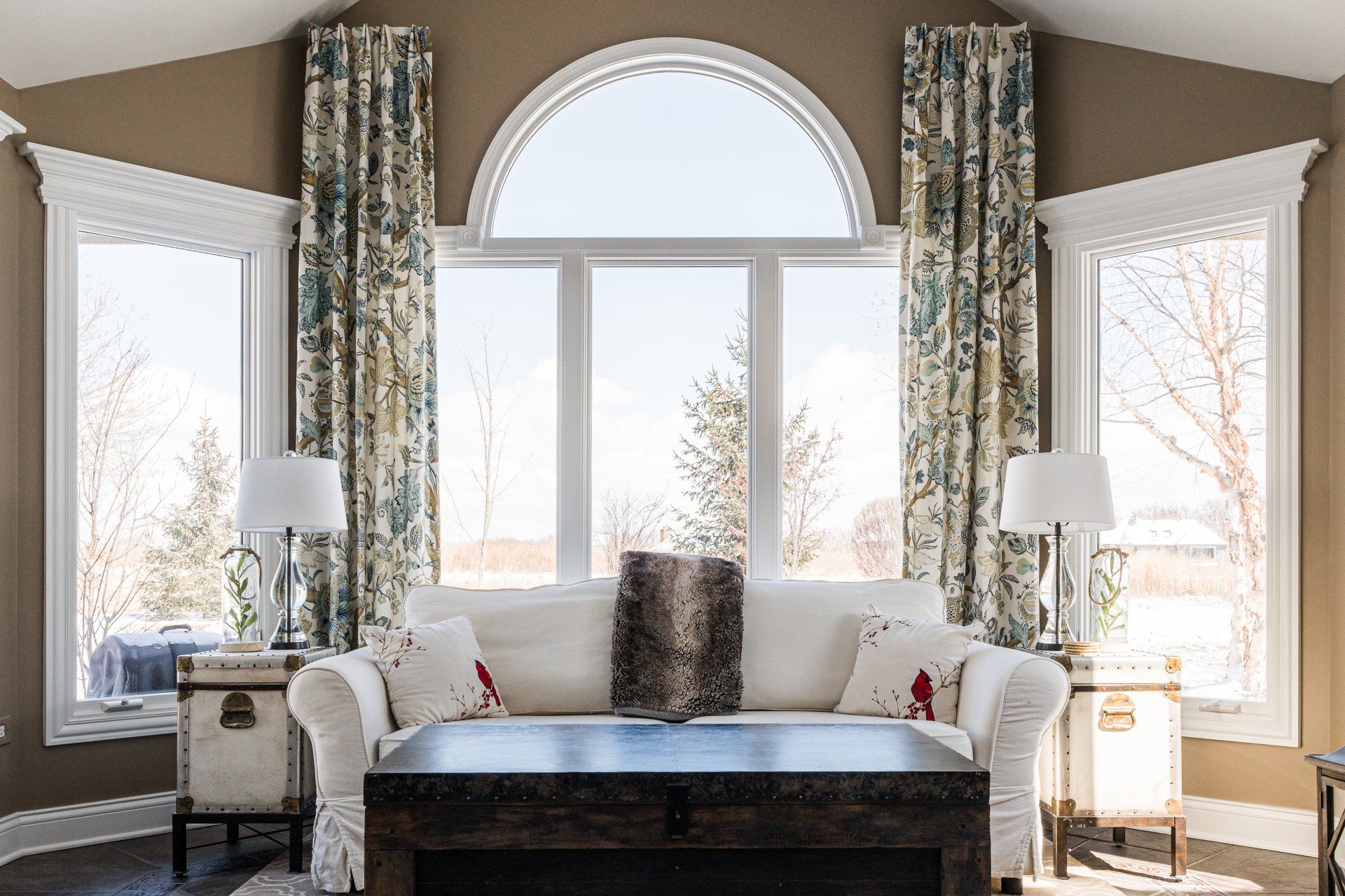 A living room with a couch , coffee table , and lots of windows.