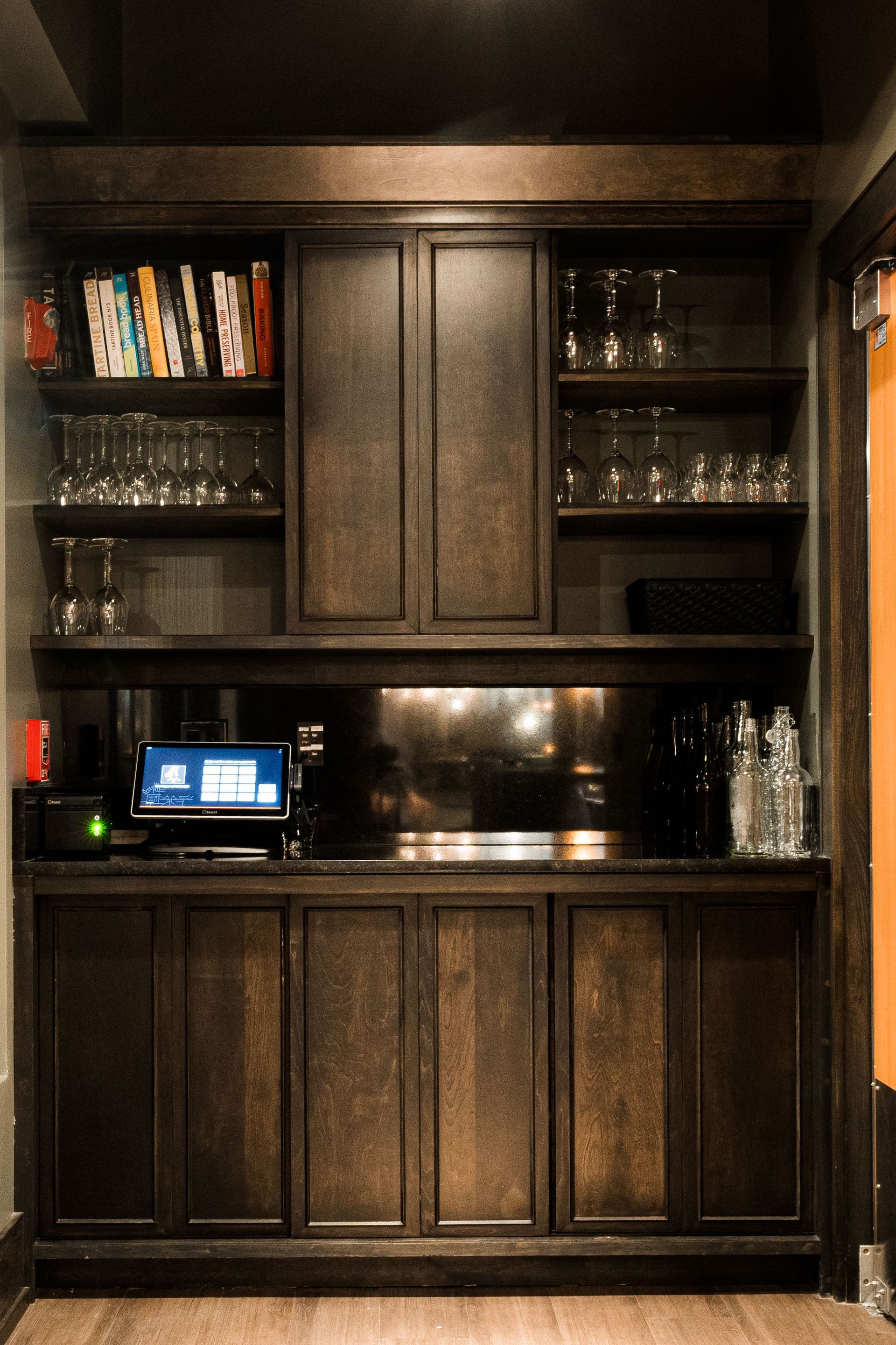 A kitchen with a lot of cabinets and shelves and a laptop on the counter.