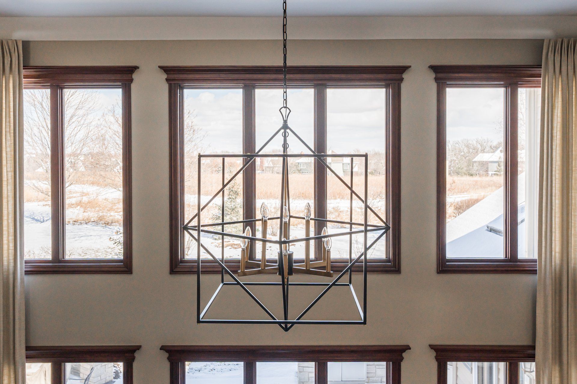 A chandelier is hanging from the ceiling in a room with lots of windows.