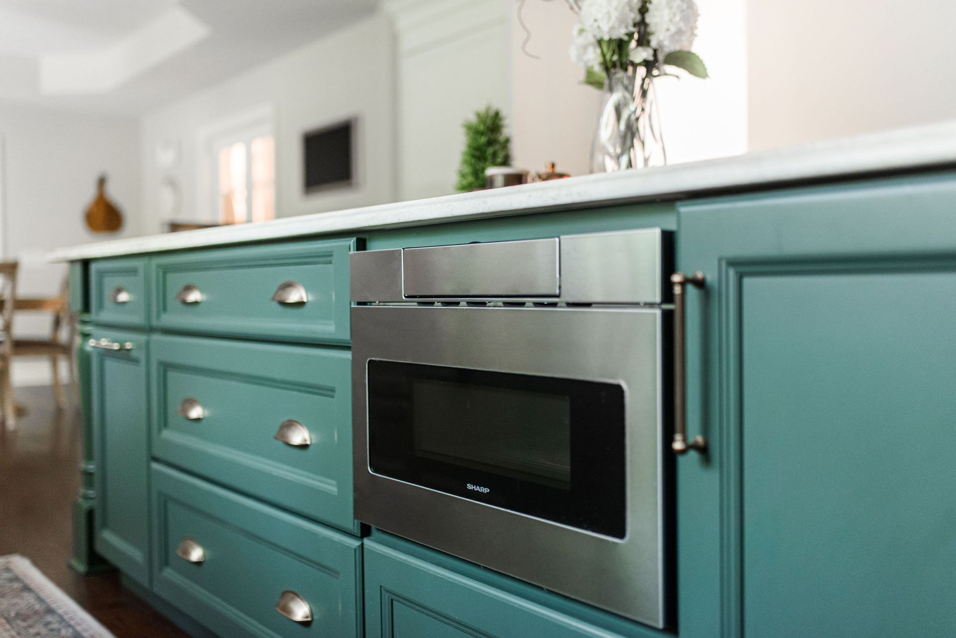 A kitchen with blue cabinets and a stainless steel microwave oven.