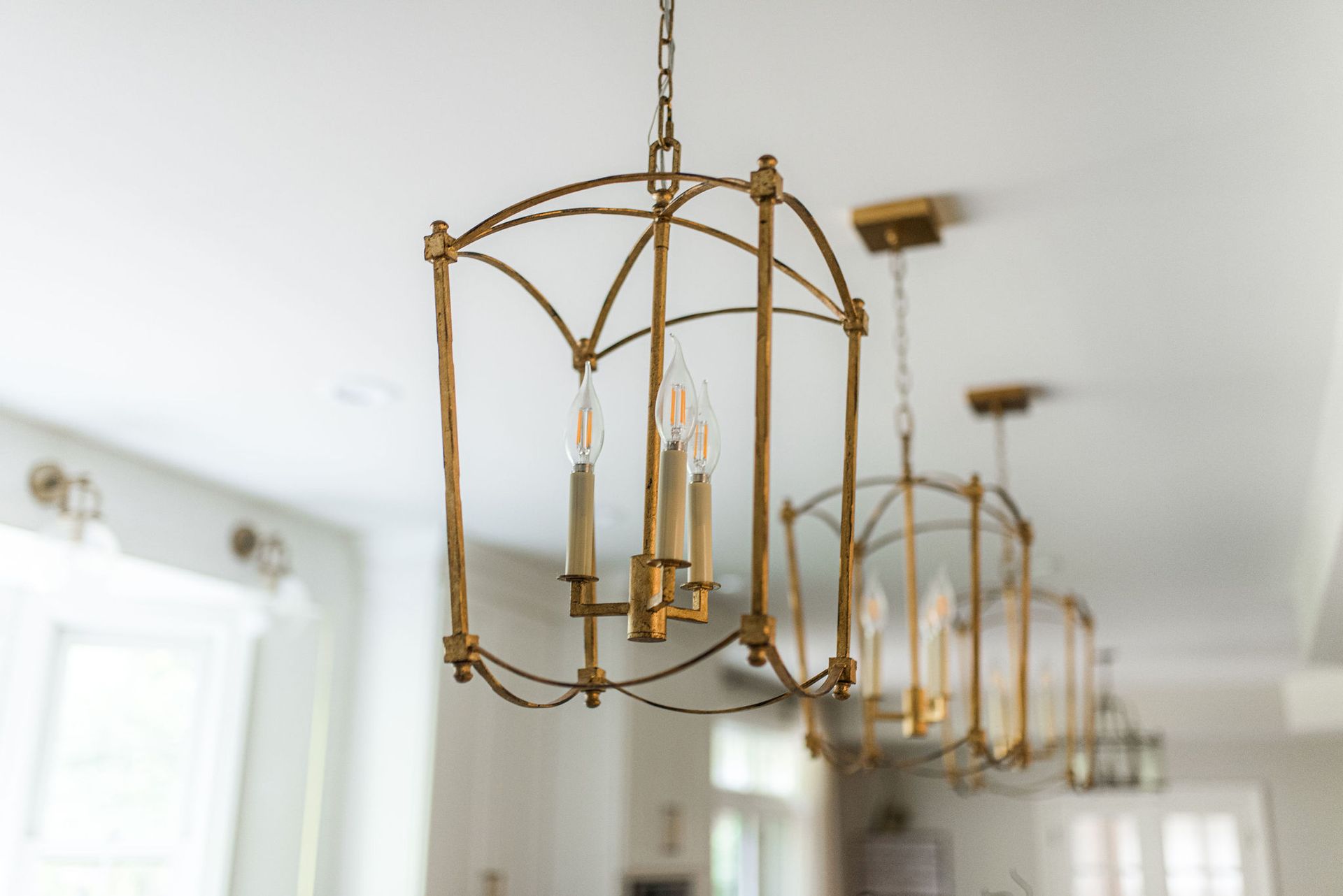 A row of gold chandeliers hanging from the ceiling in a kitchen.