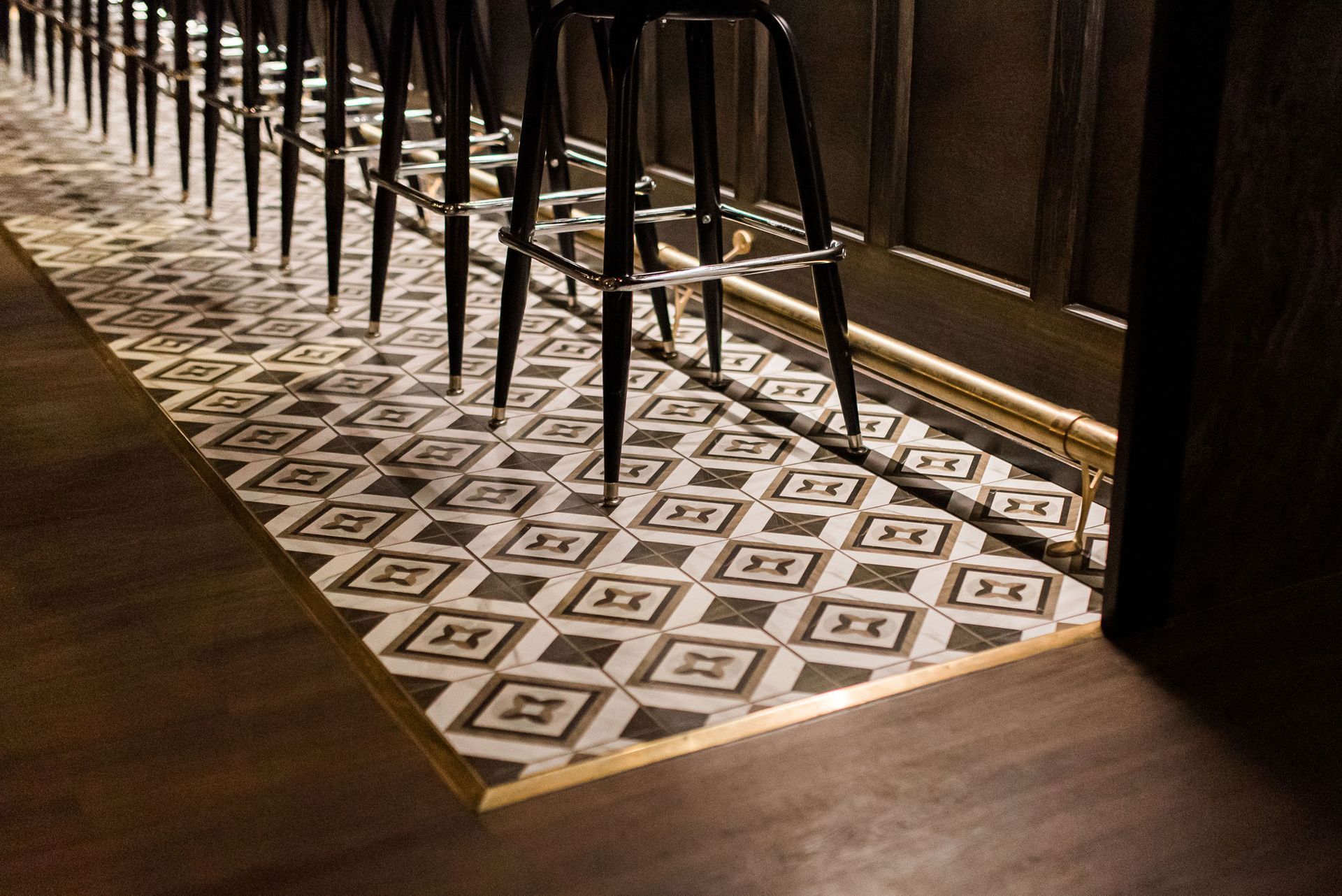 A row of bar stools are lined up on a tiled floor.