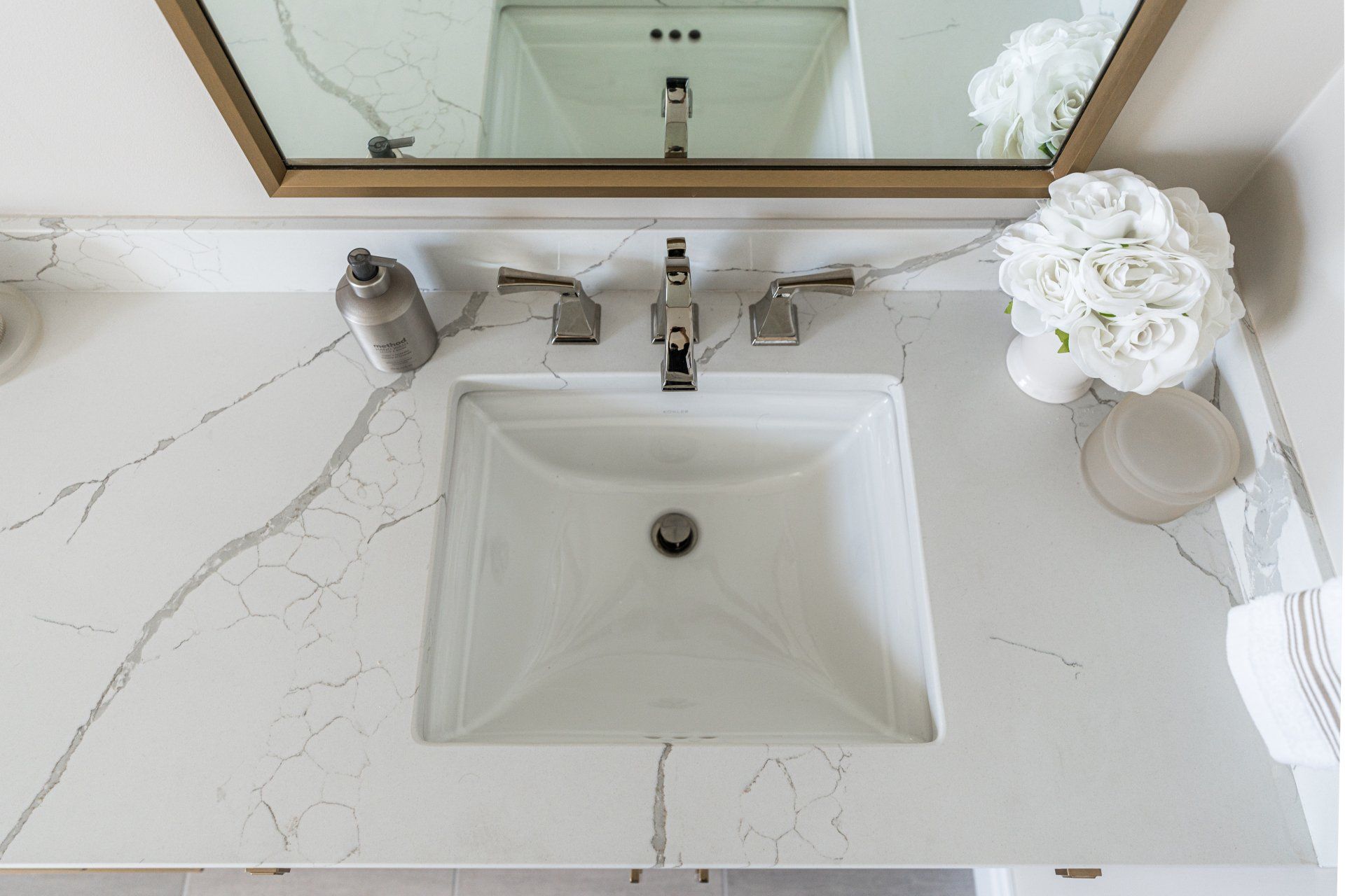 A bathroom sink with a marble counter top and a mirror.