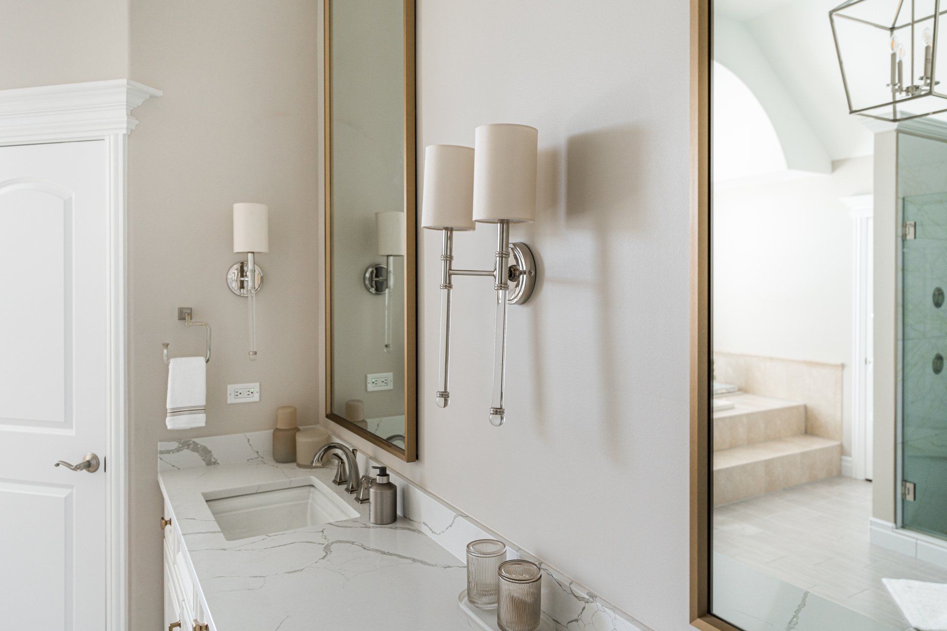 A bathroom with two sinks , two mirrors , and a walk in shower.