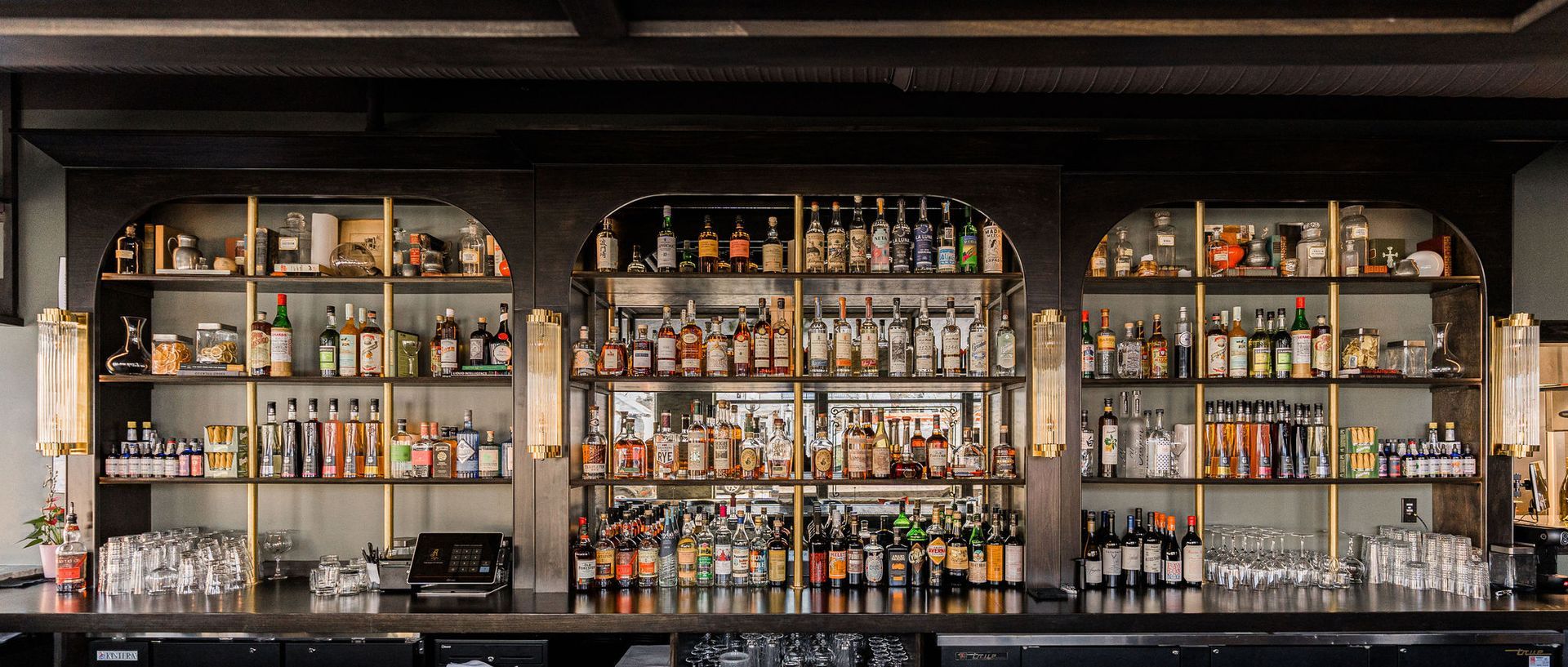 A bar filled with lots of bottles of liquor and glasses.