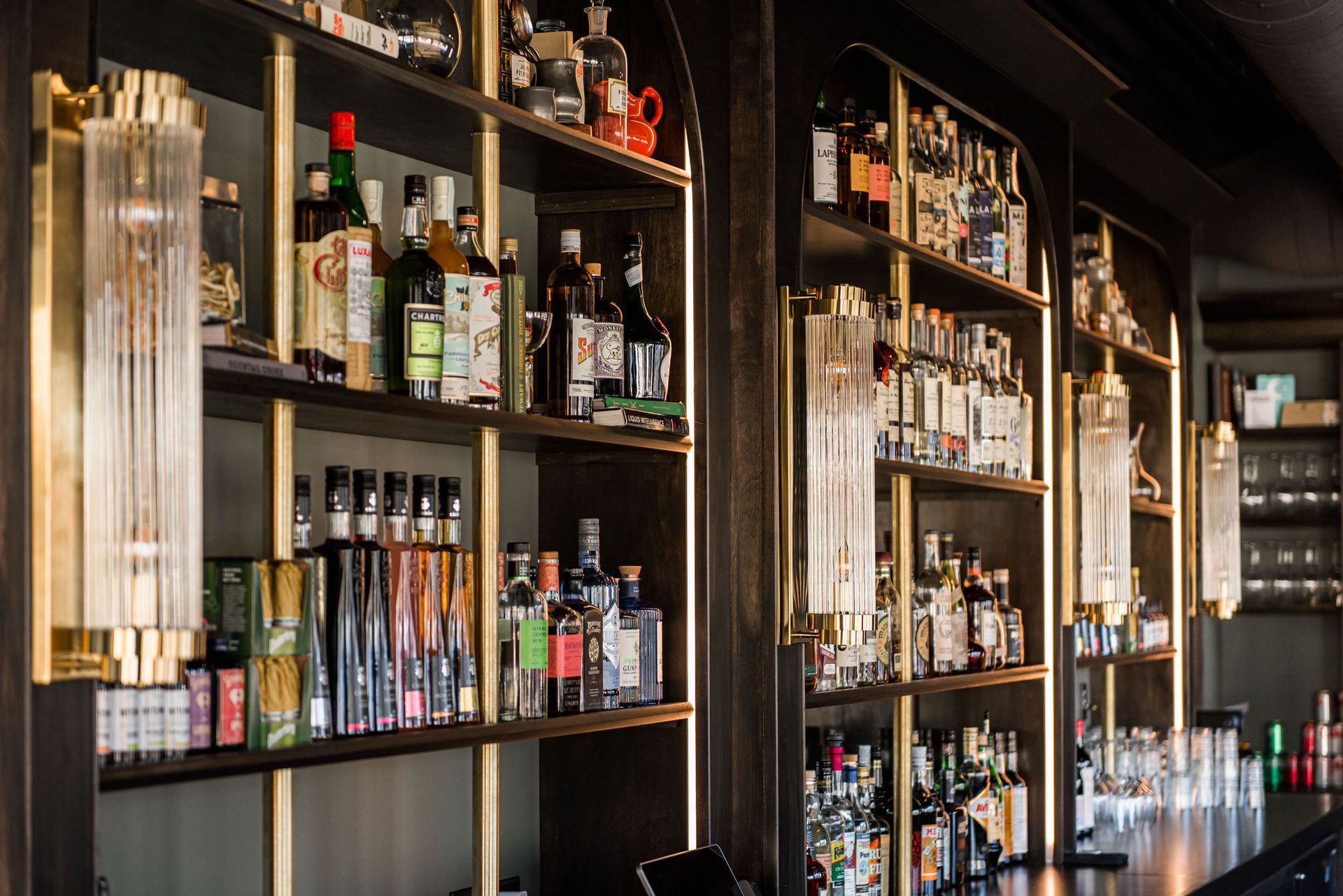 A bar filled with lots of bottles of liquor on shelves.
