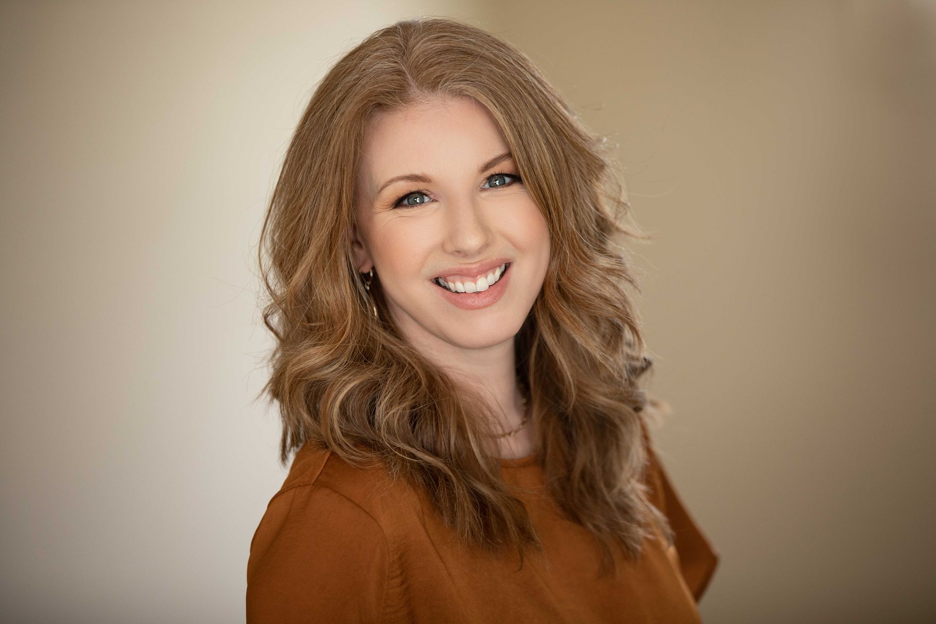 A woman in a brown shirt is smiling for the camera.