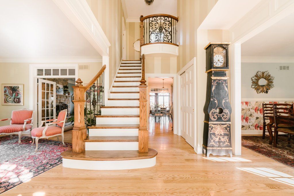 There is a grandfather clock in the middle of the room next to the stairs.