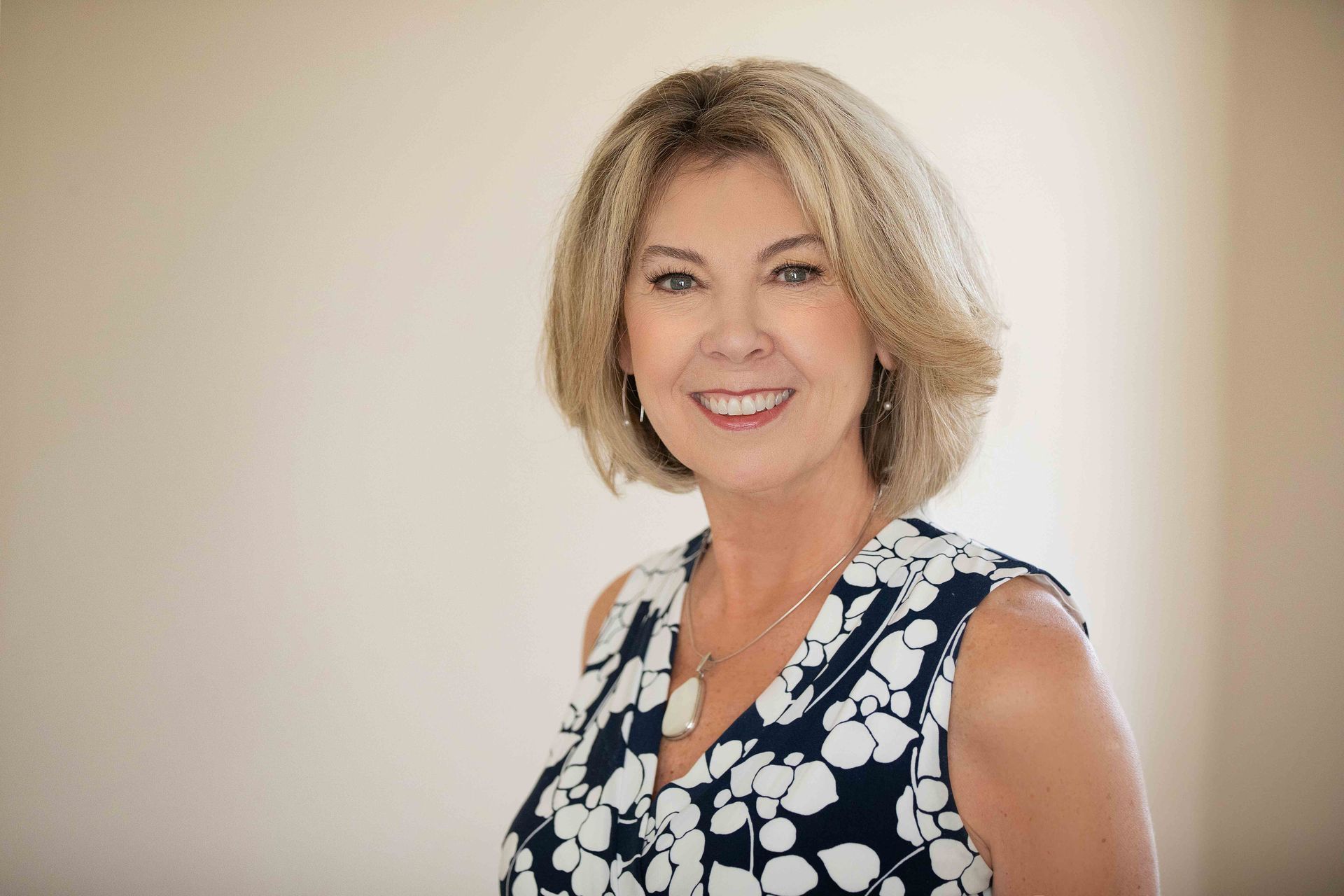 A woman in a blue and white floral dress is smiling for the camera.